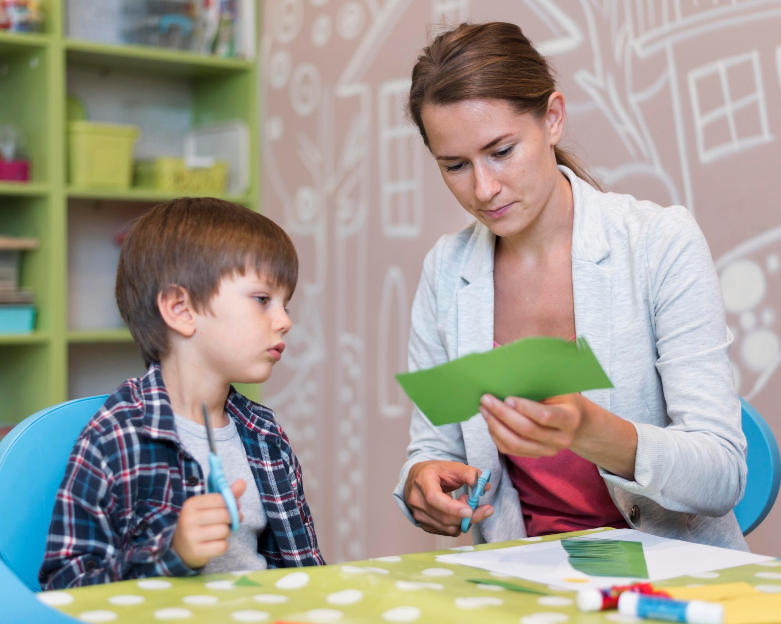 Bloom Occupational Therapist teaching a young boy to cut paper